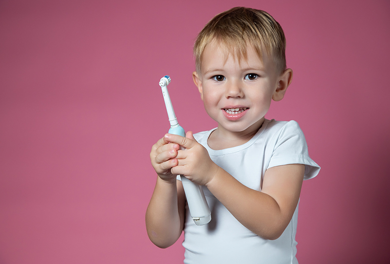 bambino vivace tiene in mano uno spazzolino elettrico
