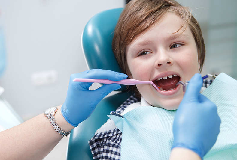 mani di dentista che ispezionano la bocca di un bambino