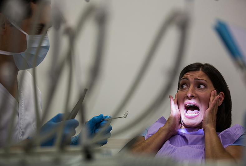 paziente impaurita dal dentisto che grida con mani alla bocca