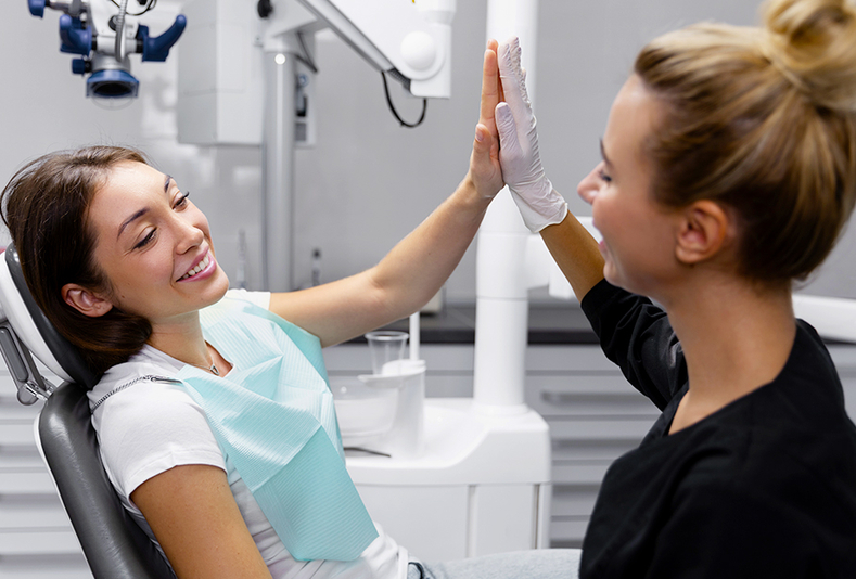 Una dentista e una paziente in uno studio odontoiatrico che si battono il cinque