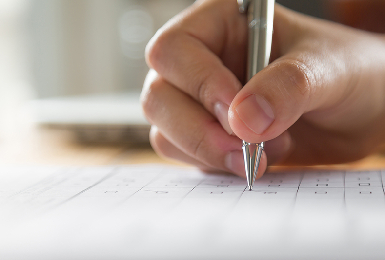 primo piano di mano con penna in mano che compila modulo cartaceo