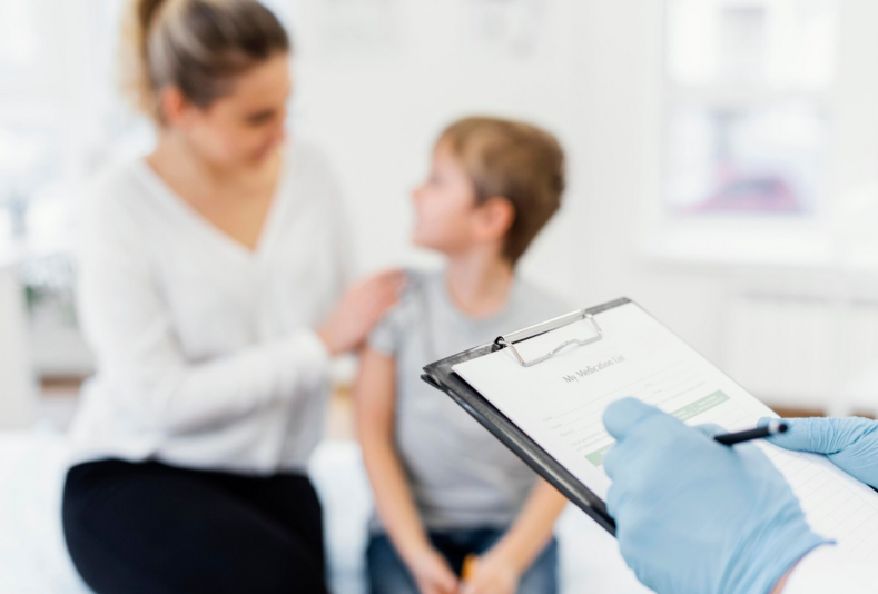mani di medico in primo piano con mamma e bambino sullo sfondo
