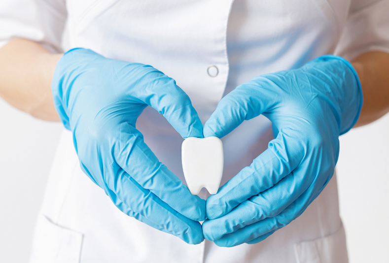 mani che formano un cuore con all'interno un modellino di dente