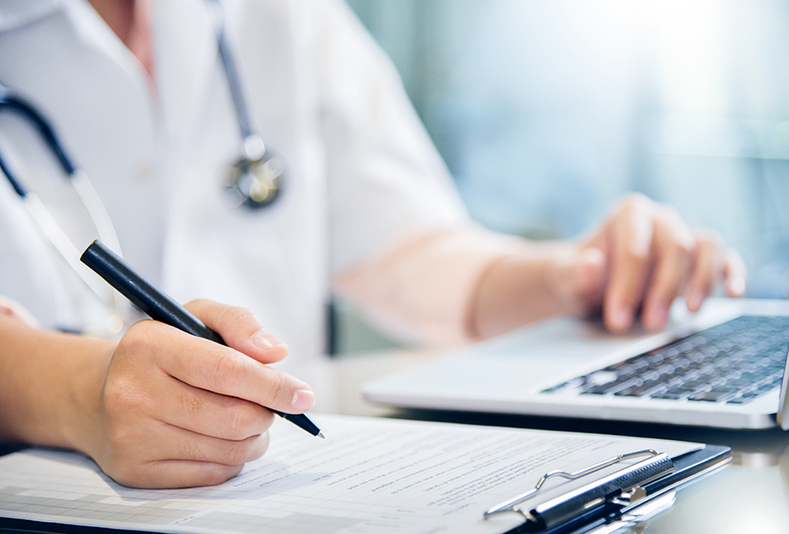 primo piano di mani di medico al pc e con blocco