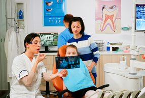 bambino con genitore sulla poltrona del dentista