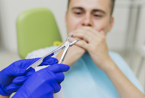 uomo dal dentista che si copre la bocca per paura