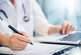primo piano di mani di medico al pc e con blocco