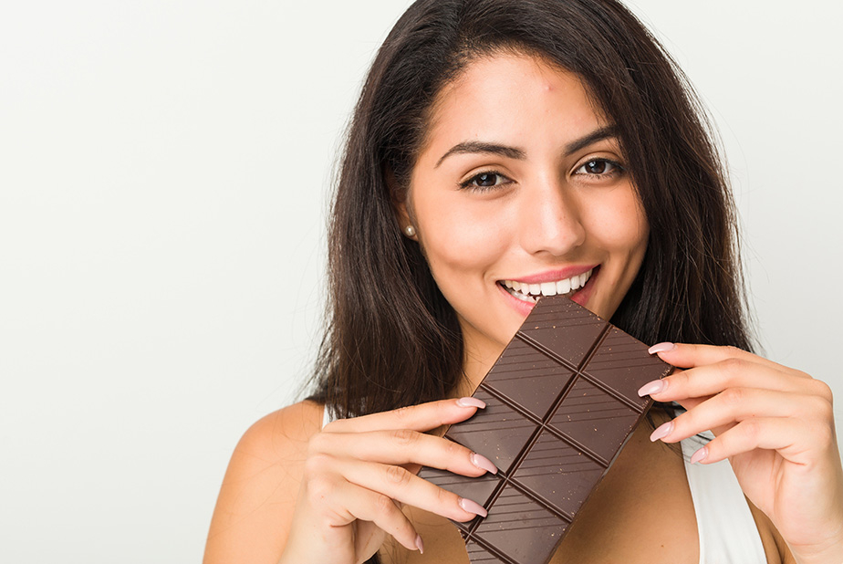 donna morde una tavoletta di cioccolato fondente