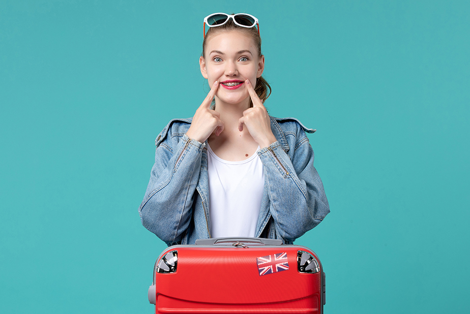 Giovane ragazza con valigia che indica sorriso