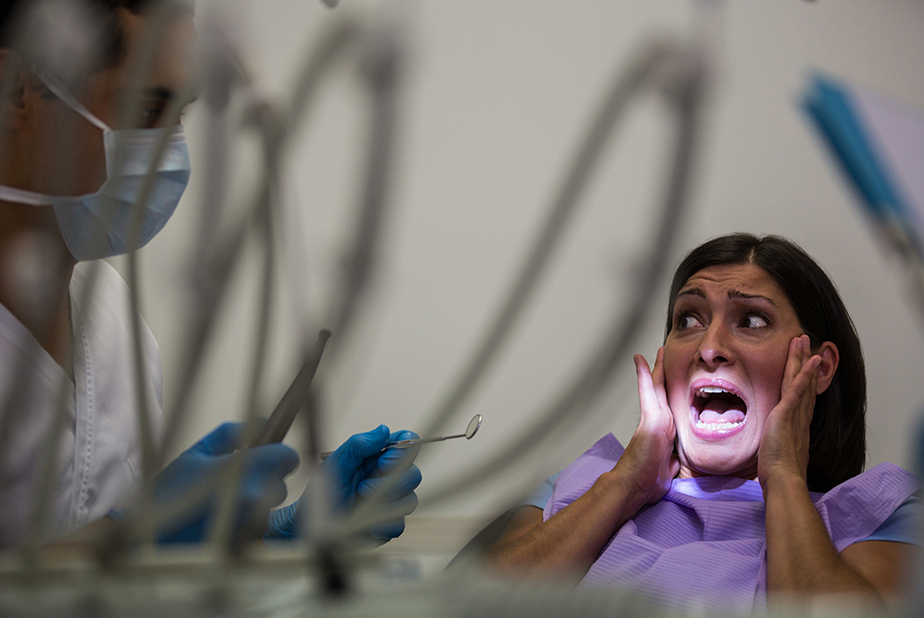 paziente impaurita dal dentisto che grida con mani alla bocca