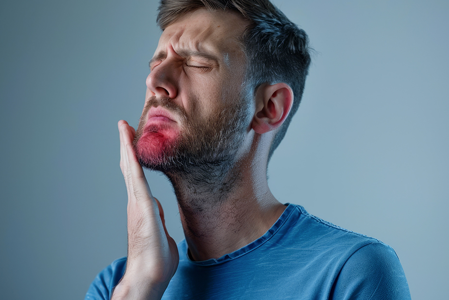 Primo piano del viso di un uomo, con una faccia sofferente per il dolore. 