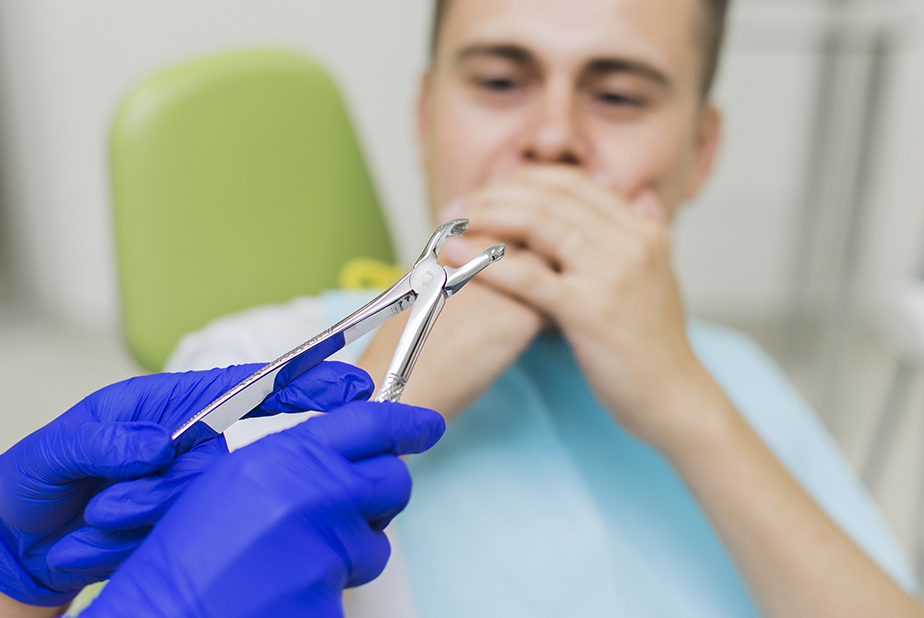uomo dal dentista che si copre la bocca per paura