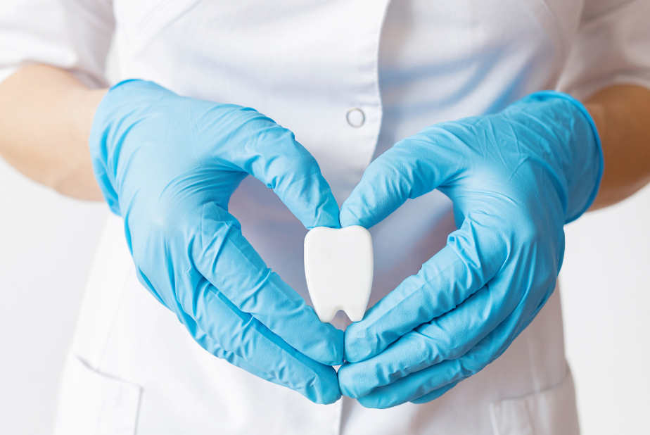 mani che formano un cuore con all'interno un modellino di dente