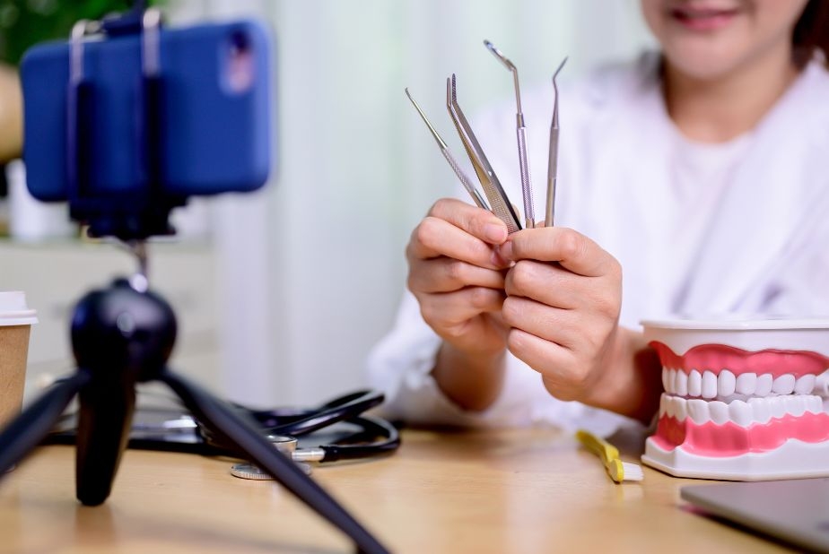 Strategie e percezioni dei professionisti sul marketing ortodontico nei social media odontoiatra davanti a fotocamera con strumenti in mano