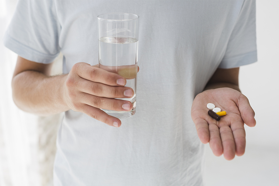 primo piano su mani di medico che tiene un bicchiere d'acqua e delle pillole